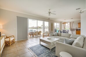 Relax in this spacious living area with a sofa, coffee table, and dining area, featuring a sliding glass door to an outdoor patio with neighborhood views.