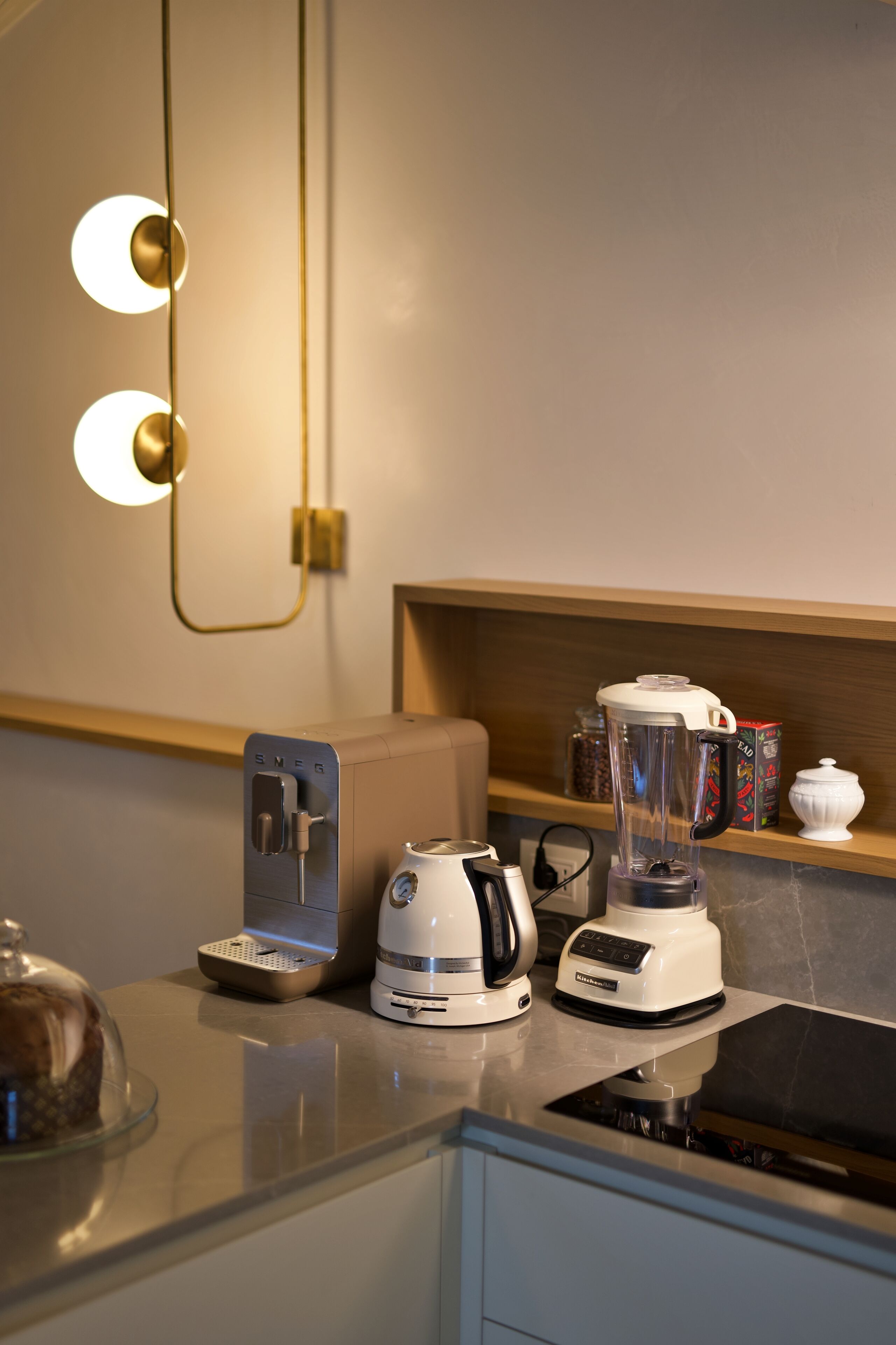 Una cocina con cafetera, tostadora, licuadora y una estantería con frascos.