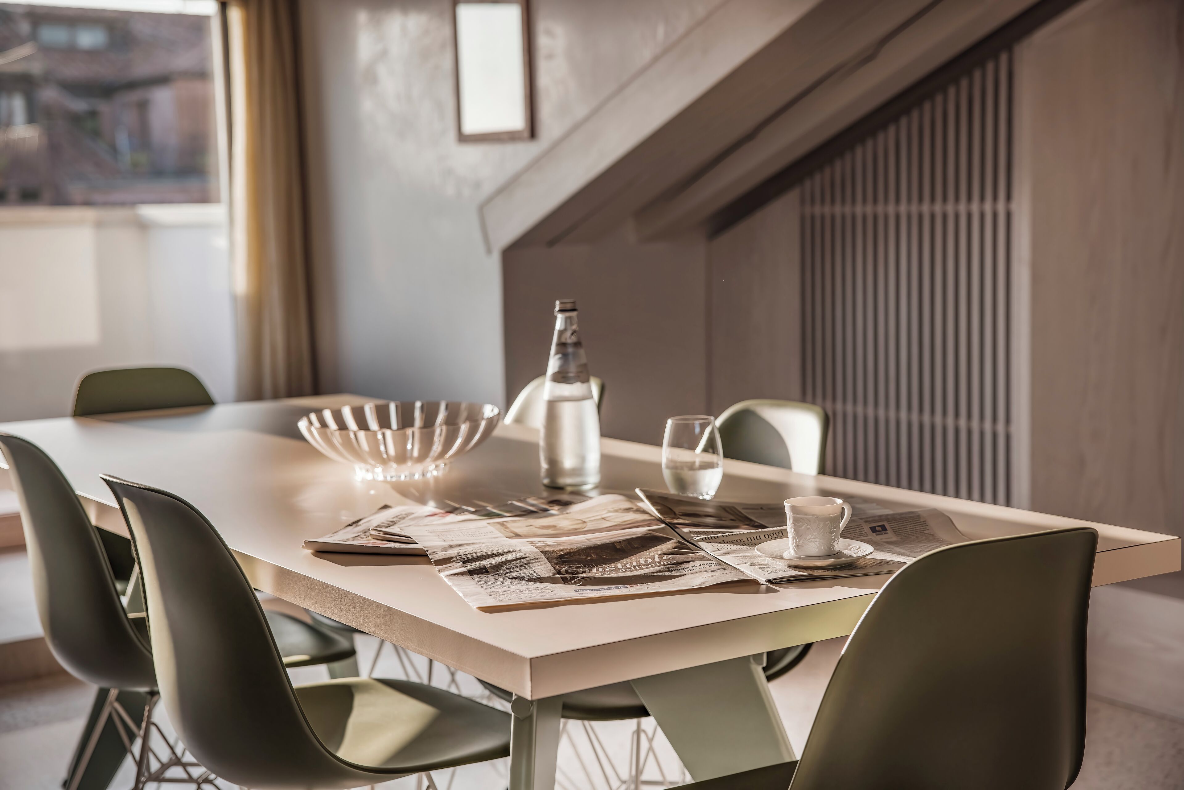Une table à manger moderne, avec un journal ouvert, une carafe en verre et une tasse.
