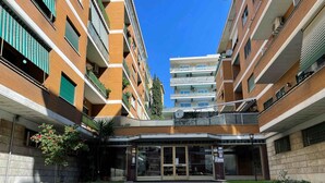 A multi-story building with a central entrance, balconies, and a clear sky. - Anastasio Vatican Rooms (Rome)