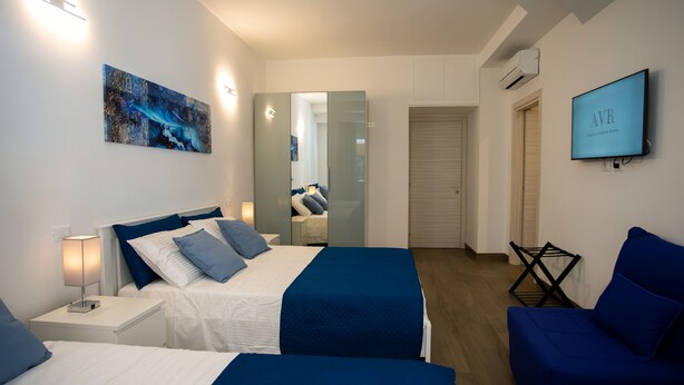 A hotel room with two beds, a TV, a painting, and a mirror. - Anastasio Vatican Rooms (Rome)