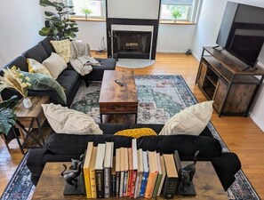 Relax in this inviting living room with a sofa, coffee table, fireplace, and large window.
