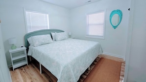 A bedroom with a bed, nightstands, a mirror, and a ceiling light fixture.