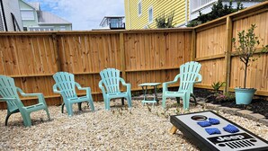 A patio area with Adirondack chairs, a small table, and a Jeep-themed mat.