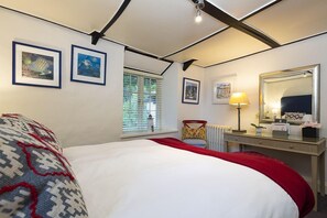 A bedroom with a bed, a desk, a chair, a lamp, and framed pictures on the wall. - 5 Bed - Rose Cottage (Torquay)