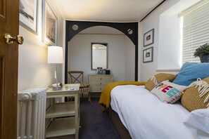 A bedroom with a bed, a desk, a chair, a dresser, a mirror, and a radiator. - 5 Bed - Rose Cottage (Torquay)