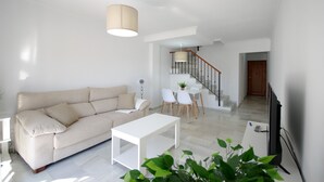 A modern living room with a sofa, a coffee table, and a dining area with chairs and a table. - 135 Livingtarifa Luna (Tarifa)