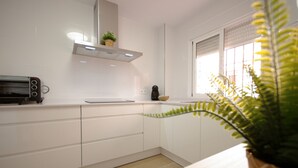 A modern kitchen with white cabinets, a toaster, and a window with blinds. - 135 Livingtarifa Luna (Tarifa)
