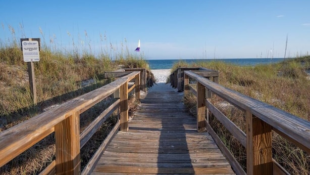 A wooden boardwalk leading to a beach with a sign indicating 'No Swimming'.