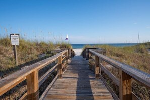 A wooden boardwalk leading to a beach with a sign indicating 'No Swimming'.