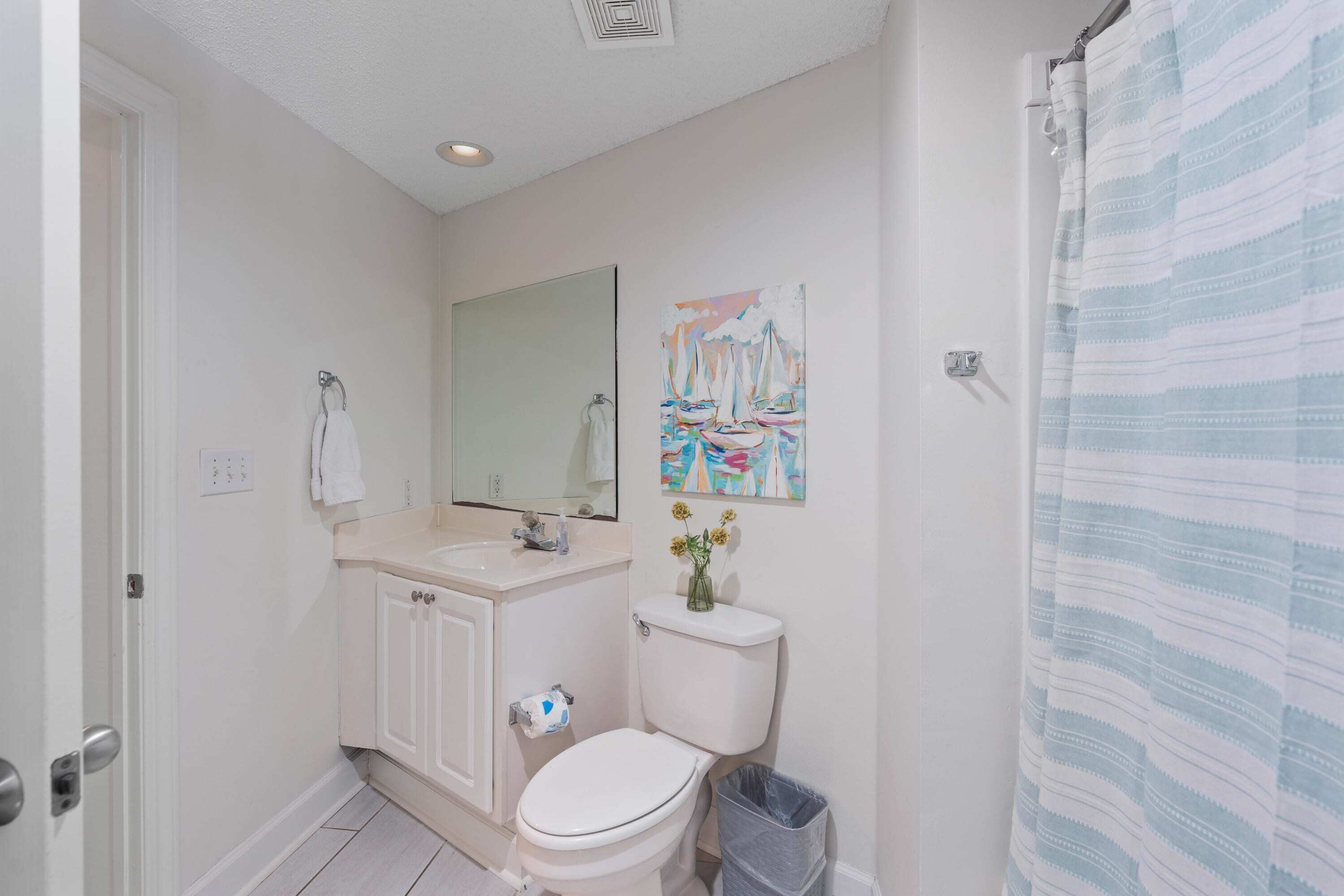 Ein Badezimmer mit Toilette, Waschbecken, Spiegel und einem Bild an der Wand.
