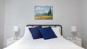 Ein Schlafzimmer mit einem Bett, zwei Nachttischen und einem Bild an der Wand.