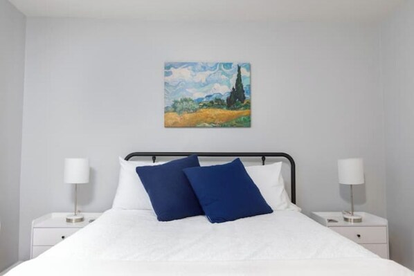 Ein Schlafzimmer mit einem Bett, zwei Nachttischen und einem Bild an der Wand.