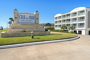 A sign for 'Casa del Mar Suites and Rentals' with a stone base and a clear blue sky in the background.