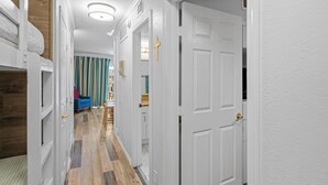 A hallway with white doors, a bunk bed, and a blue chair. - Beach Front- Cozy for Family In Casa Del Mar (Galveston)