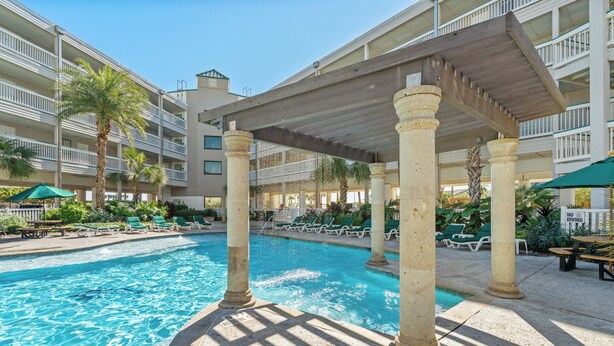 A pool area with columns, lounge chairs, and a covered seating area. - Beach Front- Cozy for Family In Casa Del Mar (Galveston)
