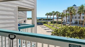 A balcony with a view of a parking lot, palm trees, and a building with a dome. - Beach Front- Cozy for Family In Casa Del Mar (Galveston)