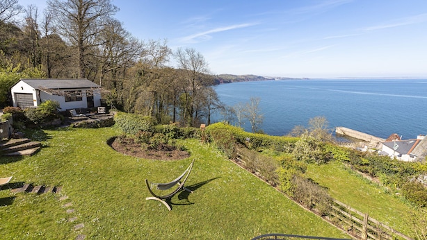 A coastal property with a grassy lawn, a hammock, and a view of the sea. - 3 Bed Cove Cottage (Torquay)