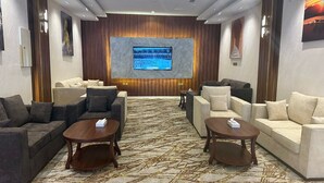 A conference room with a large screen, two sofas, and two coffee tables.