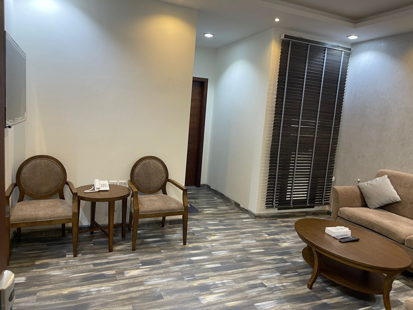 A hotel lobby with a sofa, two armchairs, a coffee table, and a telephone.