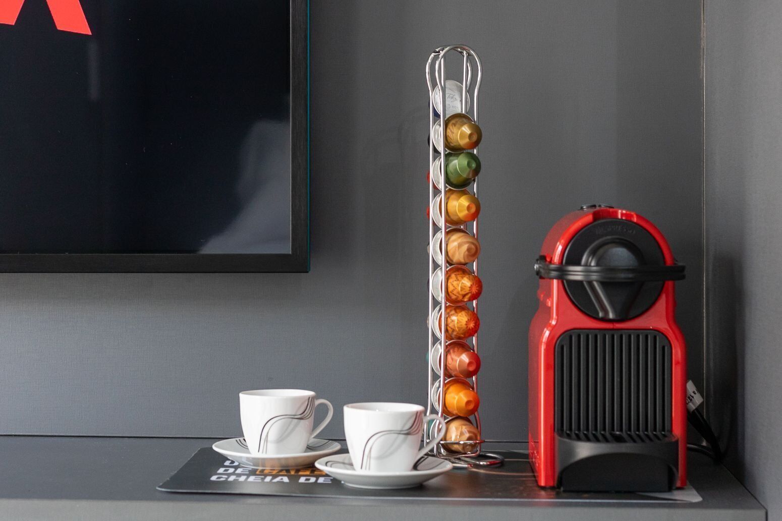 A coffee machine, a coffee cup, and a coffee grinder on a table with a placemat.