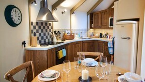 Een keuken met houten kastjes, een roestvrijstalen afzuigkap en een witte koelkast.