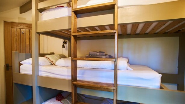 Een slaapkamer met stapelbed, houten planken en een garderobe.