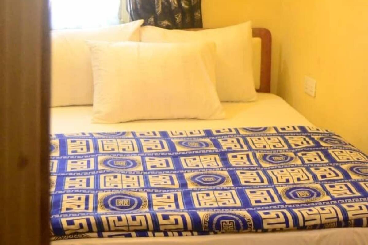 Een kamer met een bed, een raam met behang gordijnen en een airconditioning op de muur.