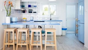 Una cocina moderna con armarios blancos, encimera azul y taburetes de madera.