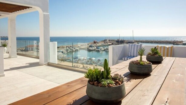 Terraza en la azotea con vistas a un puerto deportivo y al mar.