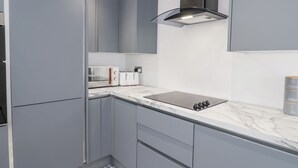 Uma cozinha moderna com armários cinza, micro-ondas embutido, torradeira e cafeteira.