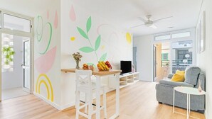 Una sala de estar moderna con comedor, un sofá gris y una pequeña mesa con fruta.