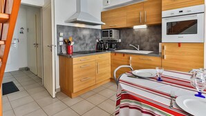 Una cocina compacta con armarios de madera, un microondas integrado y una estufa.