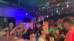 A group of people seated at a table in a dimly lit room with string lights and star decorations. - EL CURICHAL HOSTEL (Rurrenabaque)