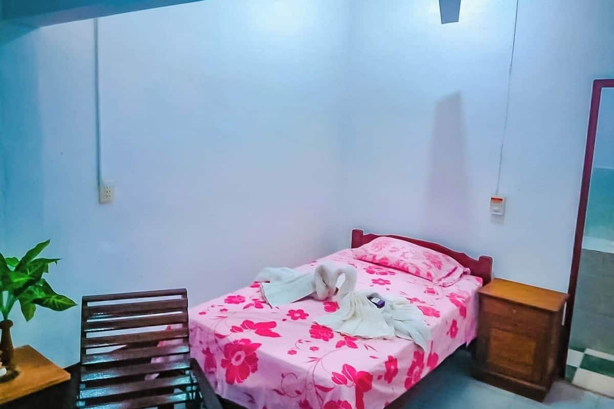A bedroom with a bed, a chair, a nightstand, and a ceiling fan.