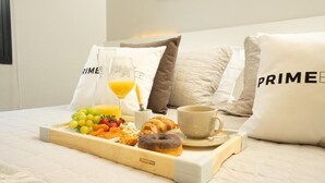 A neatly made breakfast tray on a bed with pillows labeled "PRIME" and a cup of coffee. - PRIME LOK- SP FLAT JARDINS II (São Paulo)