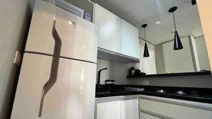 A modern kitchen with white cabinets, a black countertop, and a built-in stove. - PRIME LOK- SP FLAT JARDINS II (São Paulo)