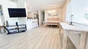 Relax in this stylish living room with a flat-screen TV, comfortable bench, and a kitchen area.