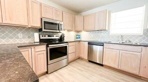 Kitchen features a double oven, microwave, and dishwasher, with a window offering natural light.