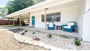 Guests can enjoy a covered porch with a blue door and comfortable seating.