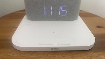 Een witte digitale klok met LED-display op een witte basis, gelabeld 'NWERK'.