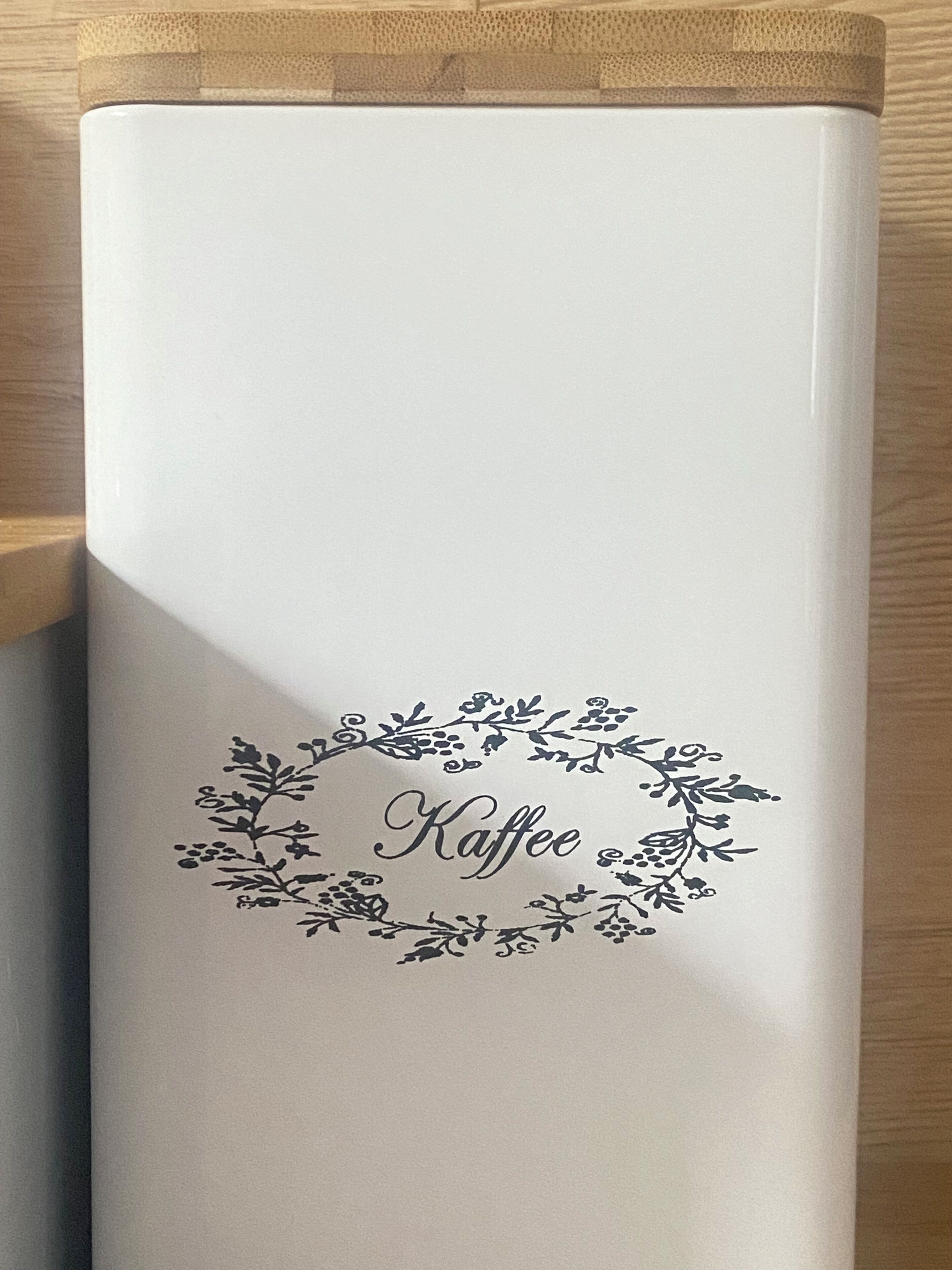 A white cylindrical object with a floral design and the word "Kaffee" in the center.