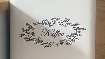 A white cylindrical object with a floral design and the word "Kaffee" in the center.