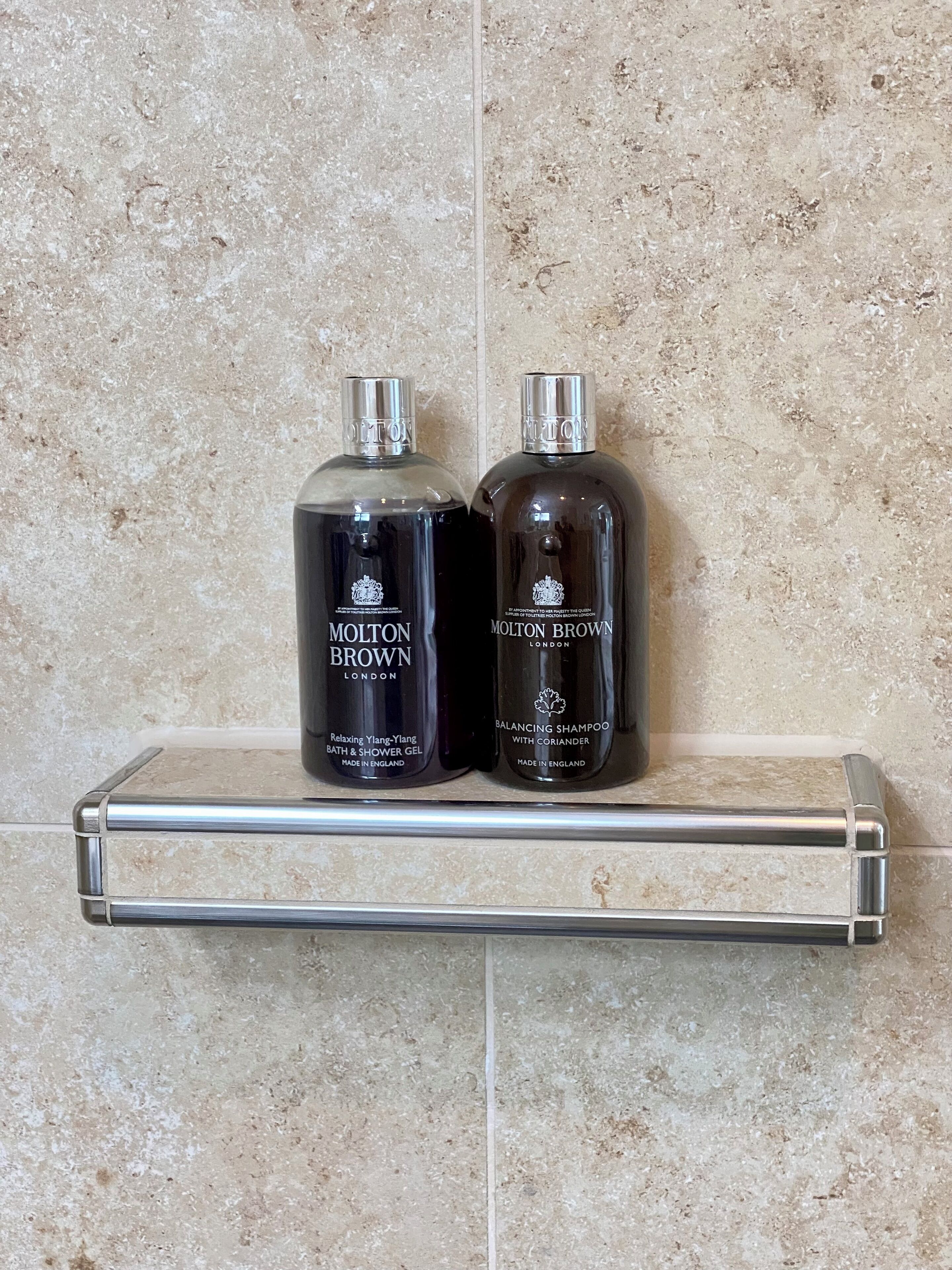Two bottles of Molton Brown products on a bathroom shelf.