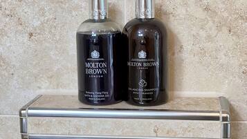 Two bottles of Molton Brown products on a bathroom shelf.
