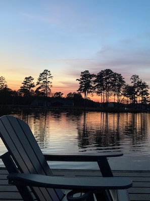 A lakeside view with a dock and a chair.