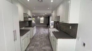 Een moderne keuken met witte kasten, donkere aanrechtbladen en een decoratieve spatwand.