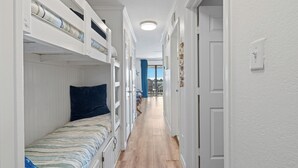 A narrow hallway with bunk beds on one side and a door on the other. - Beach Front TOP FLOOR! Ocean Views!POOL (Galveston)