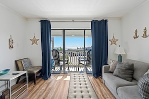 Ein Wohnzimmer mit einer Couch, einer Bank, einem Tisch und einem Balkon mit Stühlen.