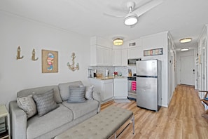 A modern kitchen with white cabinetry, a stainless steel refrigerator, and a wooden floor. - Beach Front TOP FLOOR! Ocean Views!POOL (Galveston)